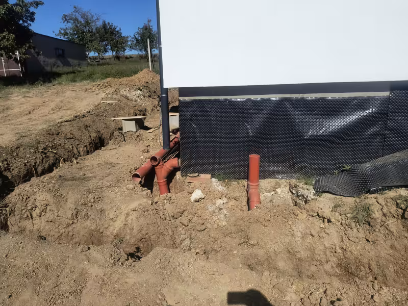 Inštalácia systému pre odvod dažďovej vody a drenáž okolo stavby.